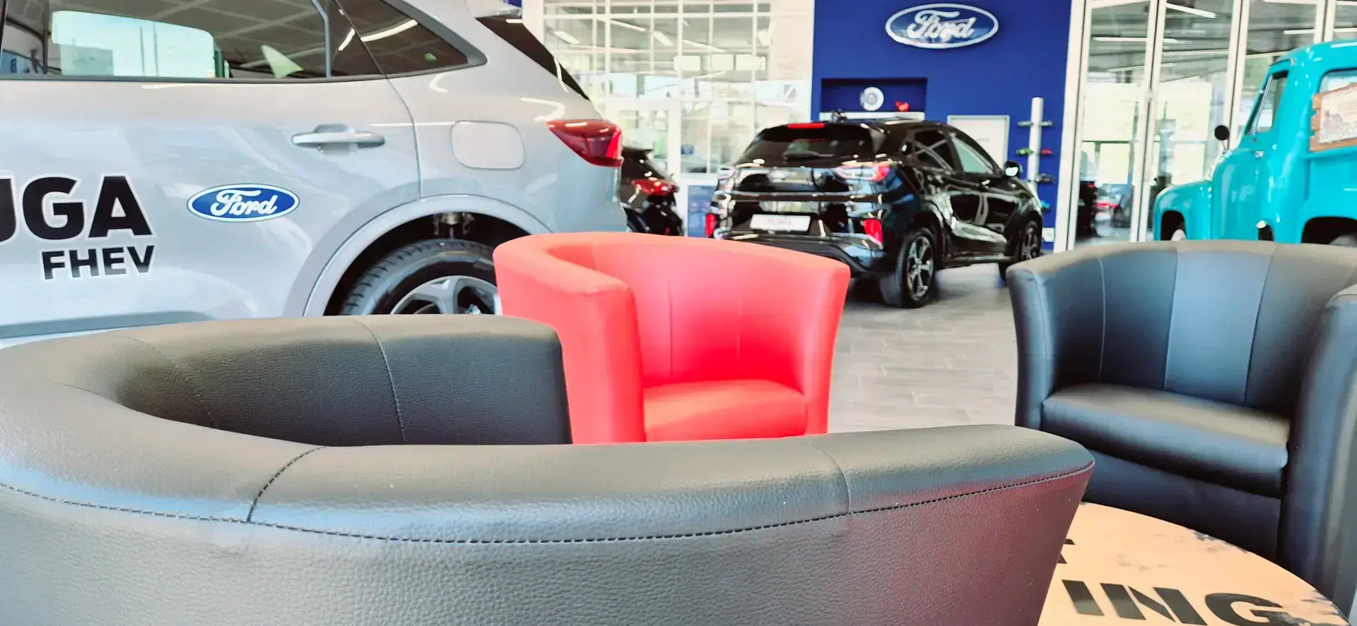 Lounge mit Sesseln im Ausstellungsraum, dahinter ein Ford Kuga